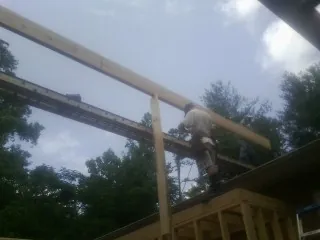 Carpenter setting a ridge beam over a new addition frame — Ice Dam Removal by Roofing Brothers in Needham Heights