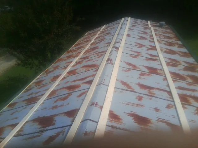 Rusted metal roof panels with new wood purlins before replacement — Storm Damage Roof Repair in Needham Heights by Roofing Brothers