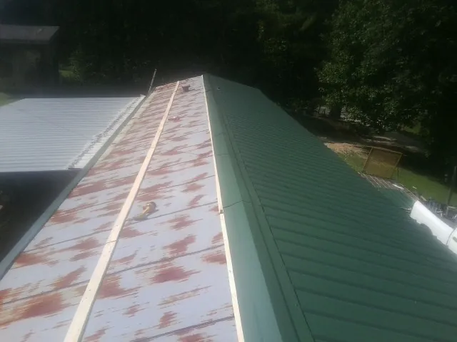 Old rusted panels beside newly installed green metal roofing — Wind Damage Roof Repair by Roofing Brothers in Needham Heights