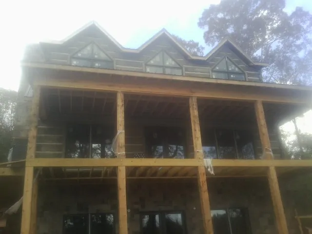 Dormers and porch framing on a large log home under construction — Roof Coating work by our crew in Needham Heights