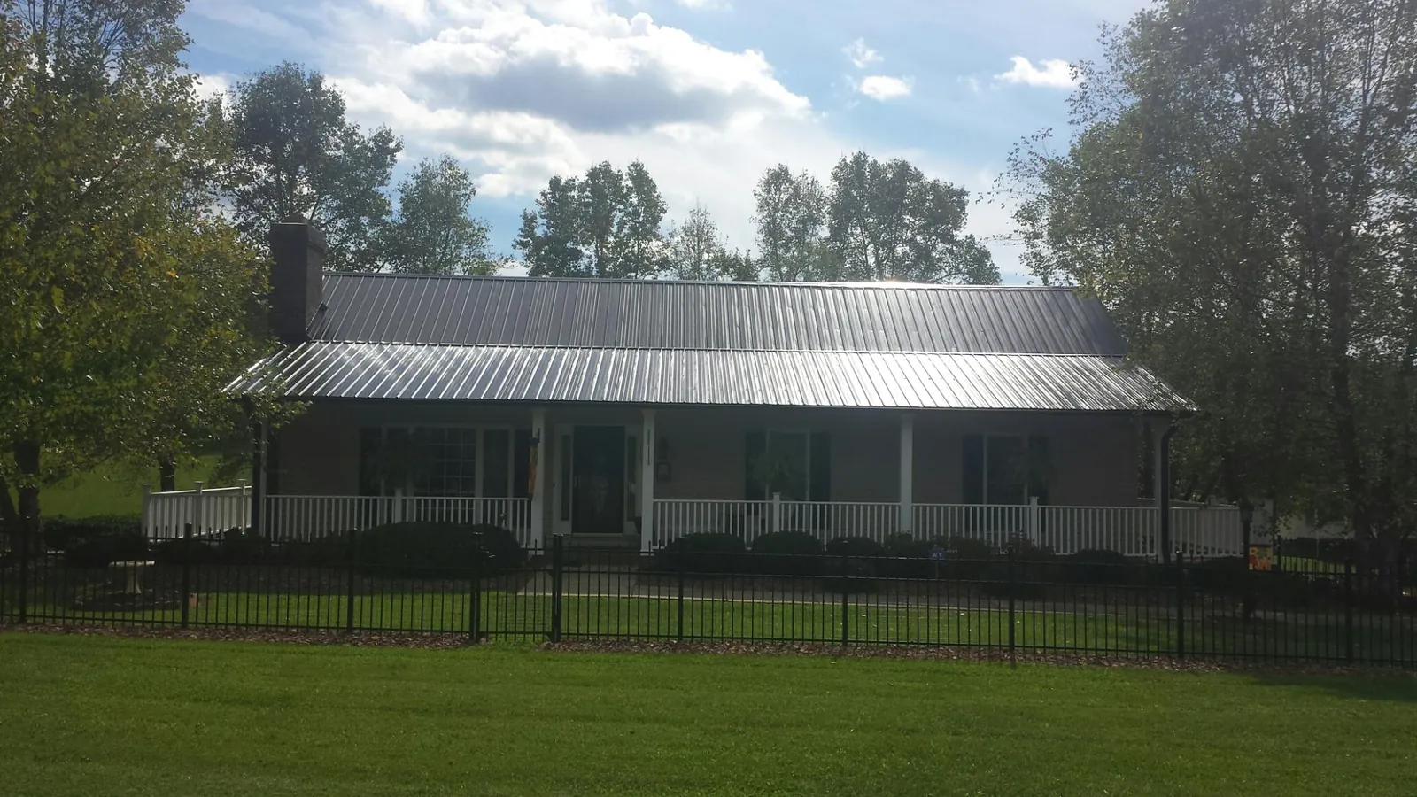 Gray metal roof on a brick ranch with a full width front porch — Gutter Guard Installation work by our crew in Needham Heights